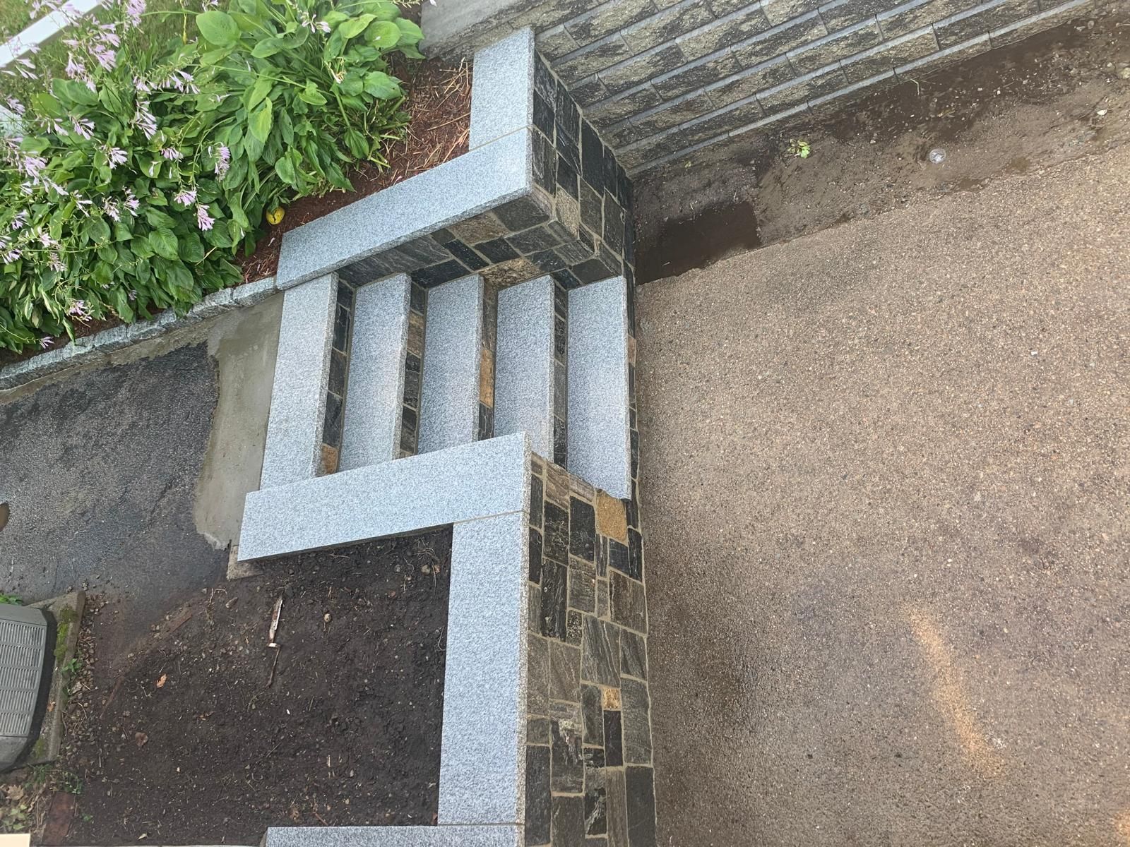 Concrete garden wall with white trim beside a brick path and greenery
