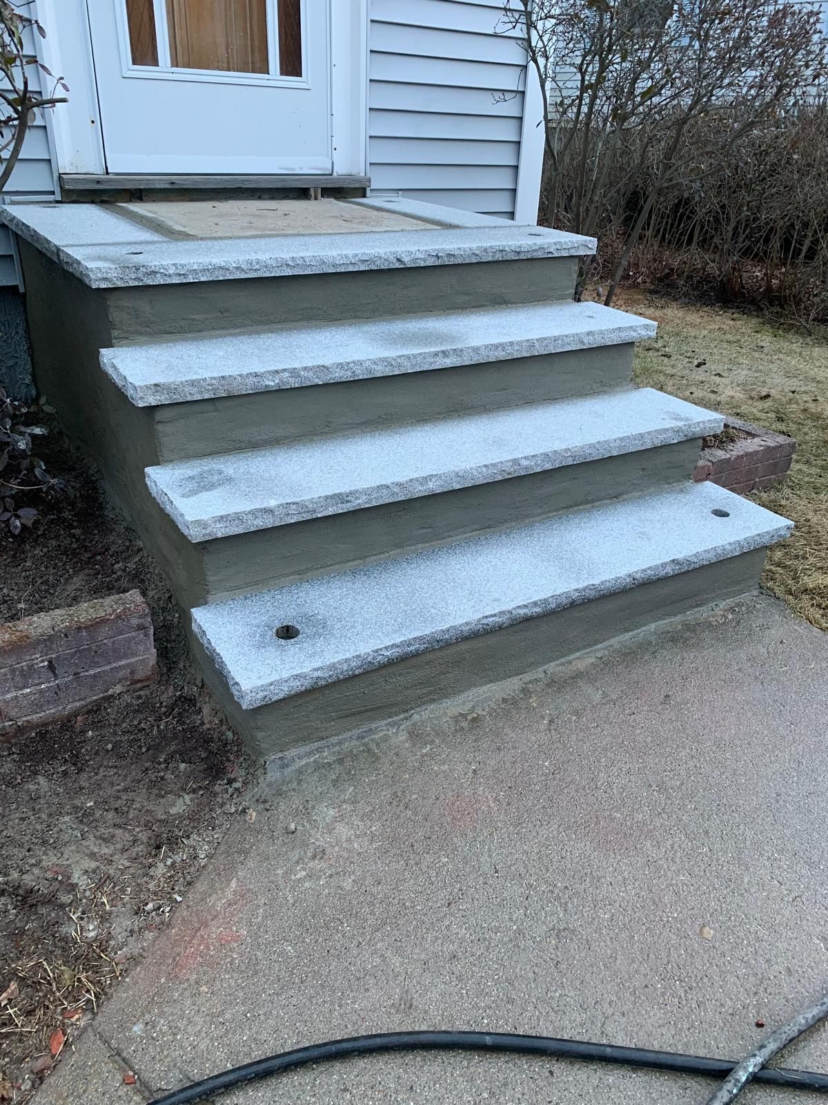 Front steps of a house with white-painted concrete stairs leading to a door
