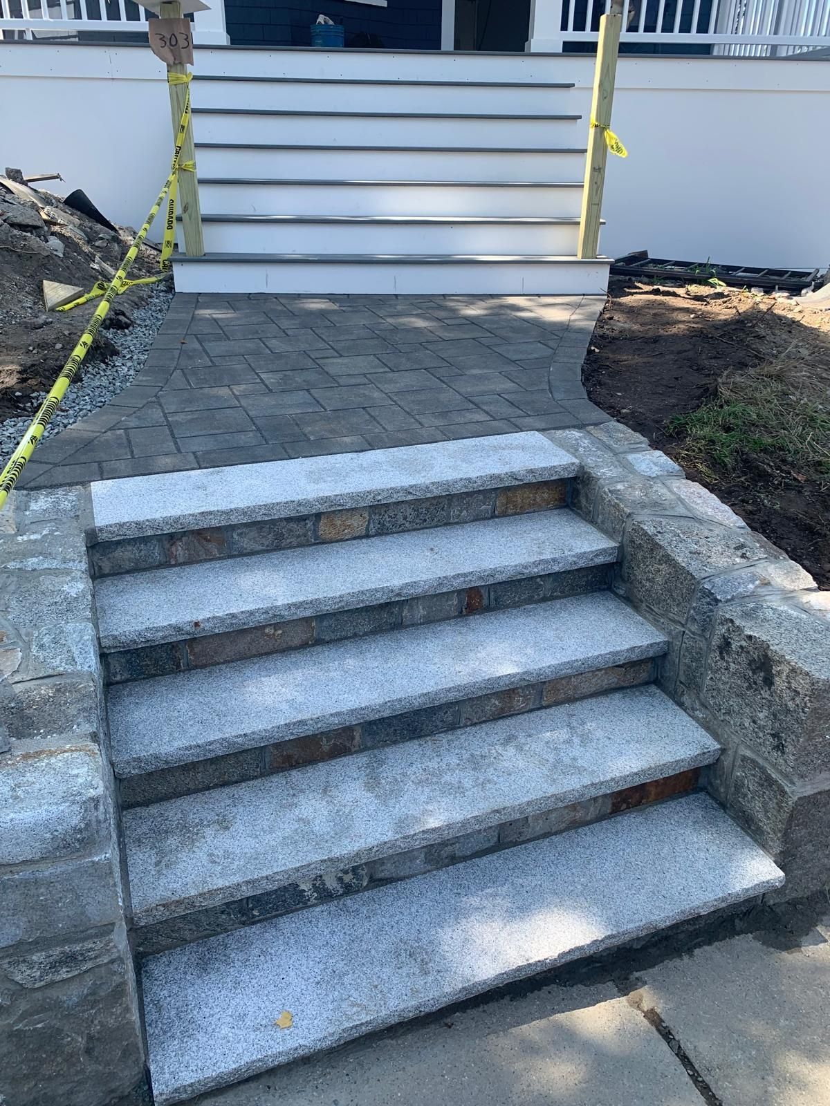 Stone steps and walkway leading up to a white porch entrance, flanked by low stone walls.