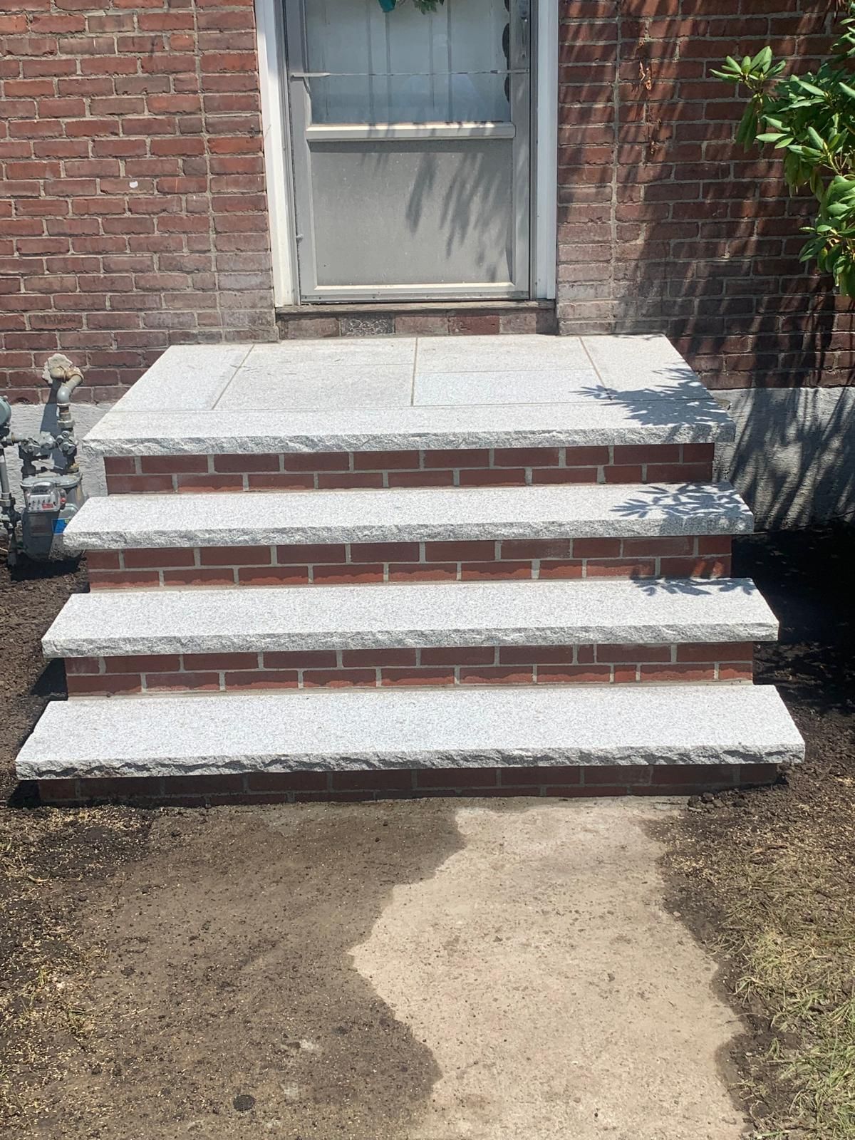 Three white-painted concrete steps leading to a closed door on a brick house.