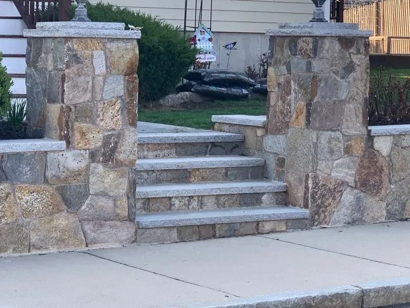 Stone staircase between two stone pillars leading up to a house entrance