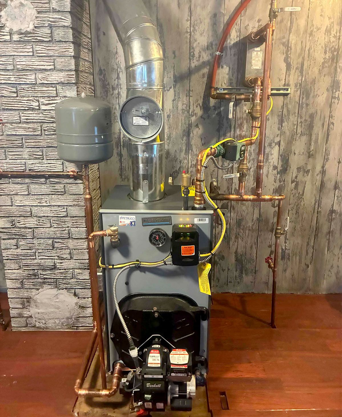 Boiler and piping system with gauges, copper pipes, and control units in a utility room