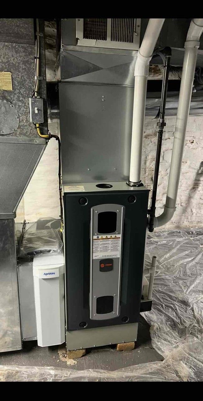 Basement furnace and water heater beside white utility pipes and insulation