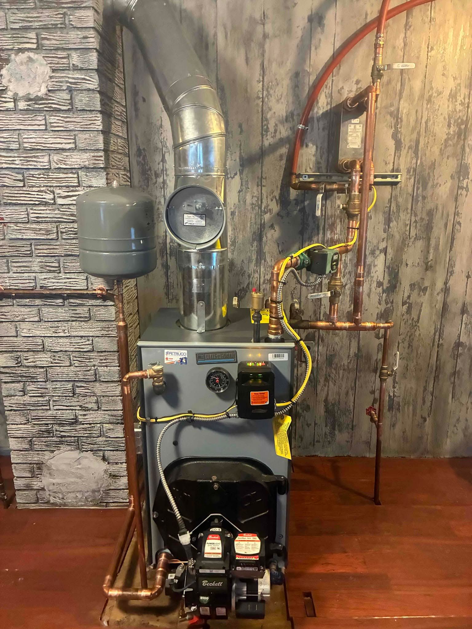 Gas furnace and HVAC ductwork installed in a basement with visible piping and wiring.