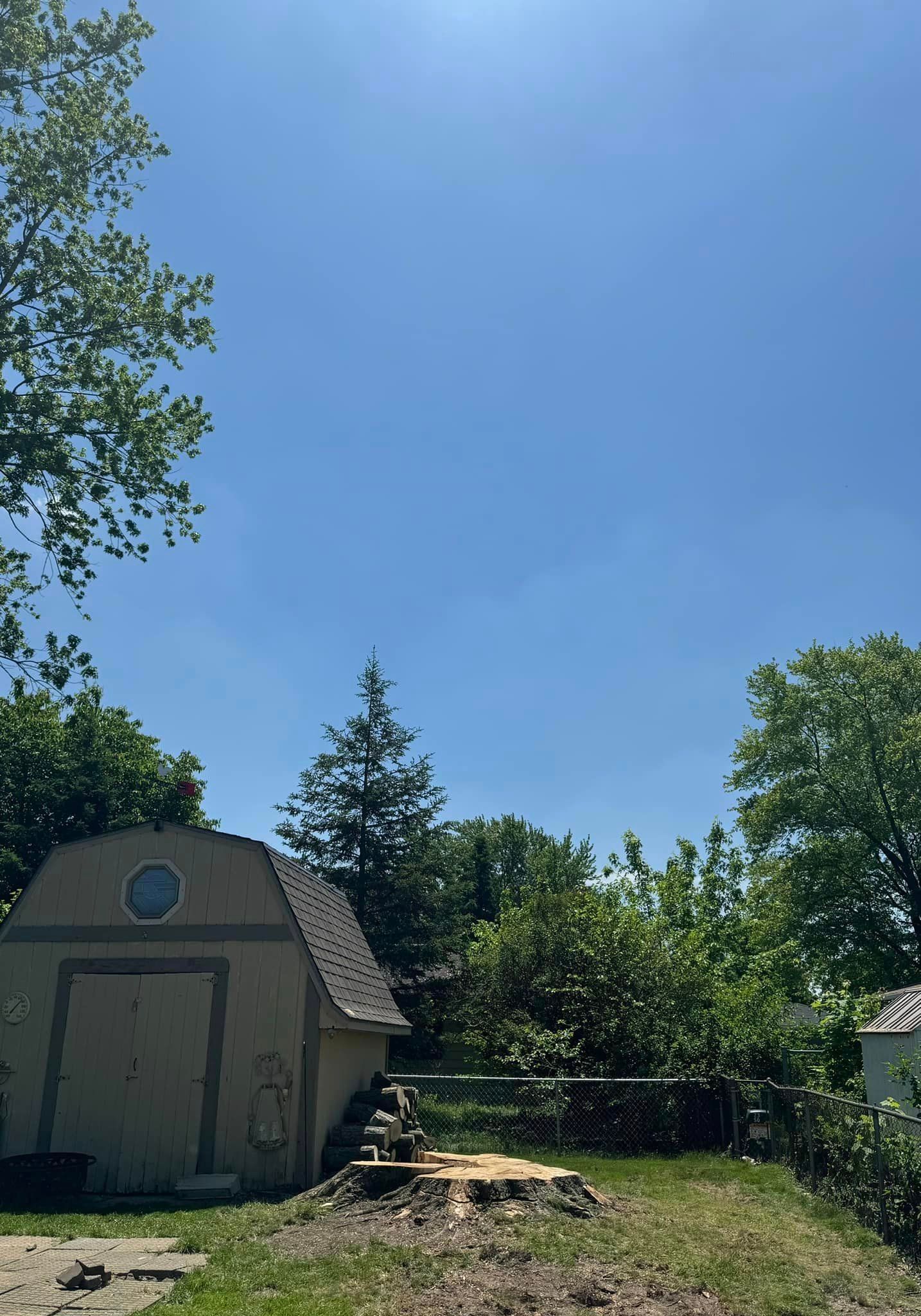 A small barn is sitting in the middle of a lush green field.