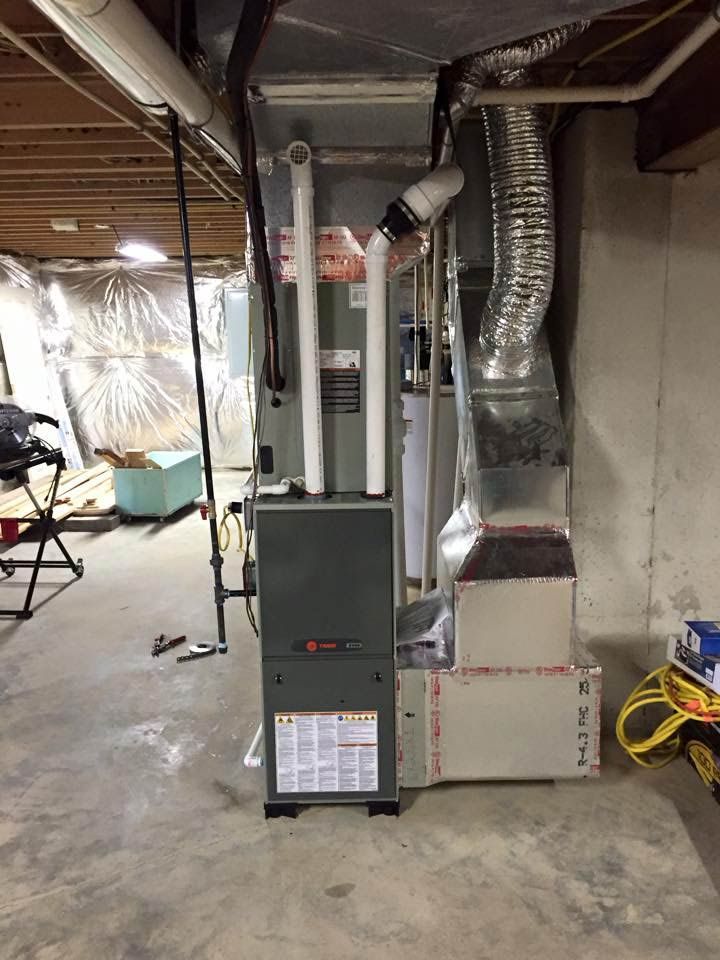 Furnace and related ductwork in a concrete basement setting. Gray and silver components are visible.