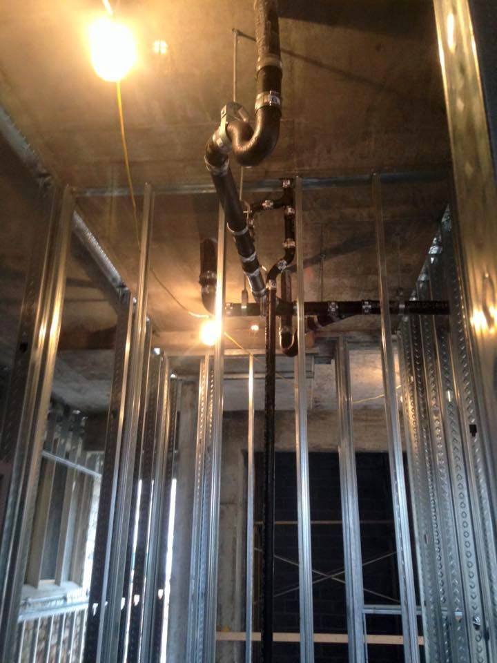 Metal framing and plumbing pipes in a construction setting, seen from a low angle.