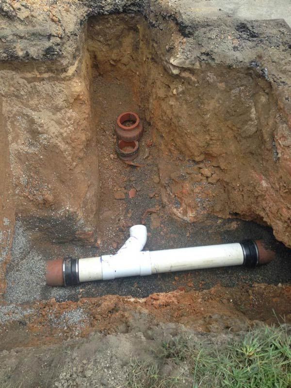 Construction site with excavated dirt revealing plumbing pipes.
