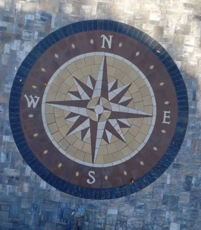 Compass rose mosaic with N, E, S, W directions in blue and tan tiles