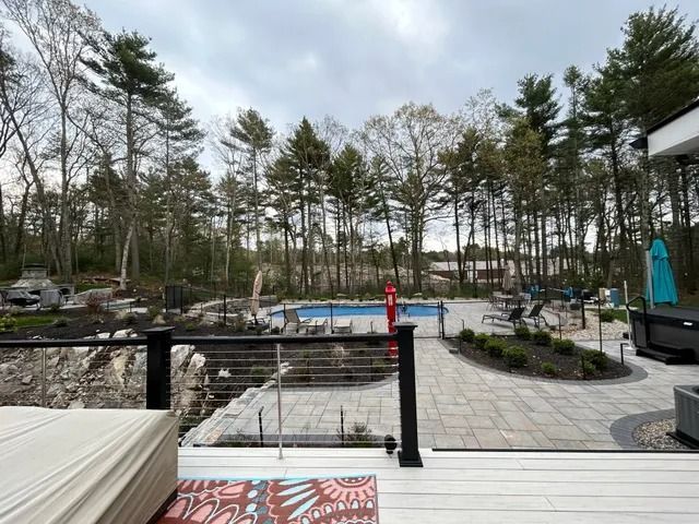 Wooded poolside patio with lounge chairs, stone paving, and a covered hot tub area
