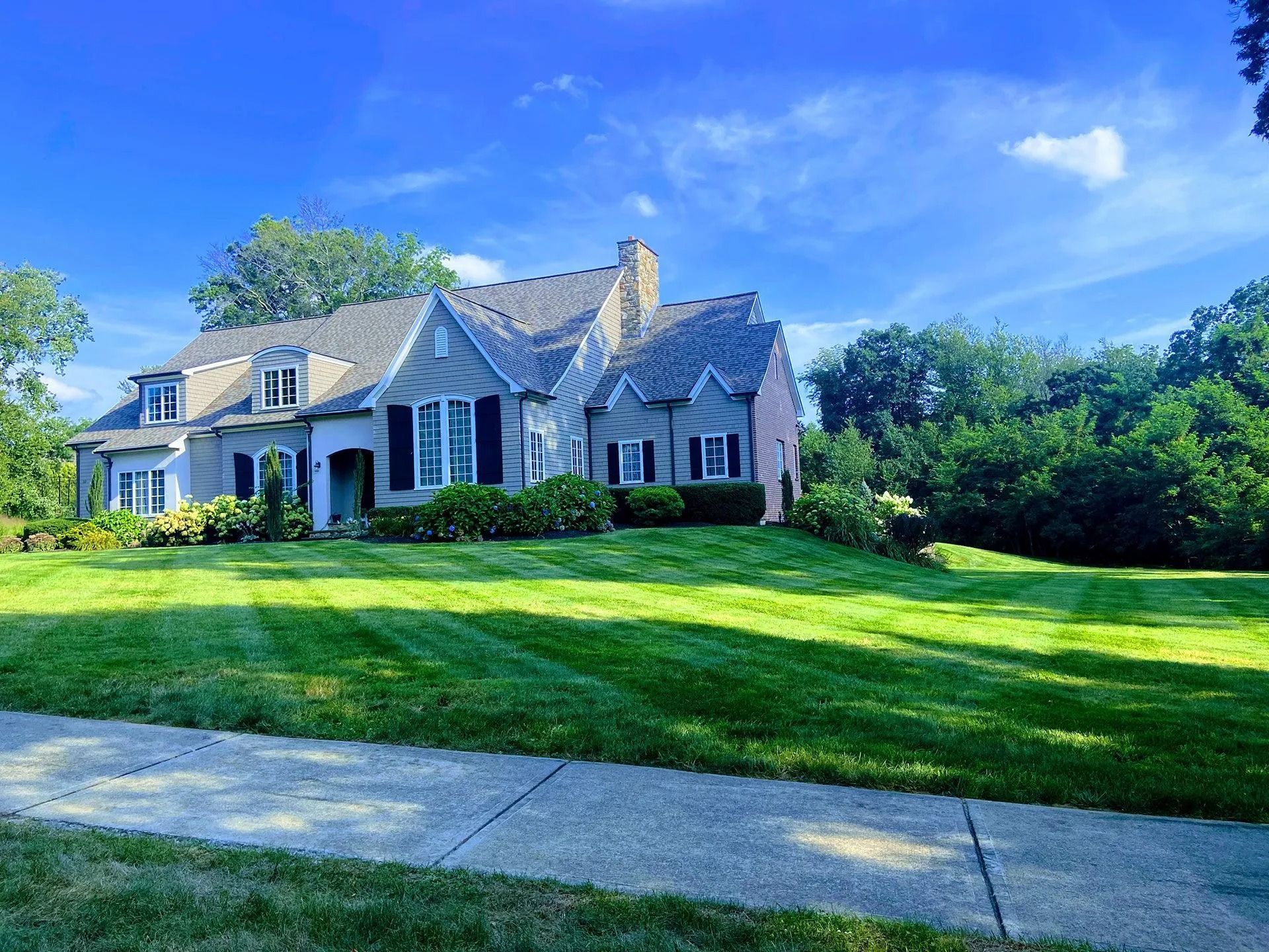 White house with stone accents on a green lawn under a bright blue sky