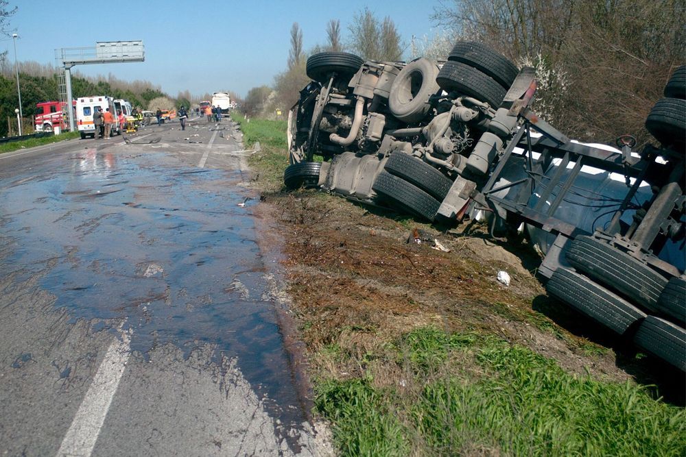 A truck is upside down on the side of the road
