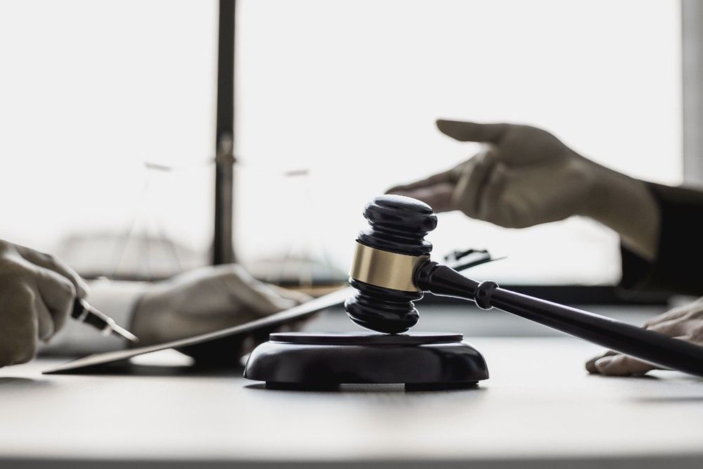A judge's gavel is sitting on a table next to a person holding a pen