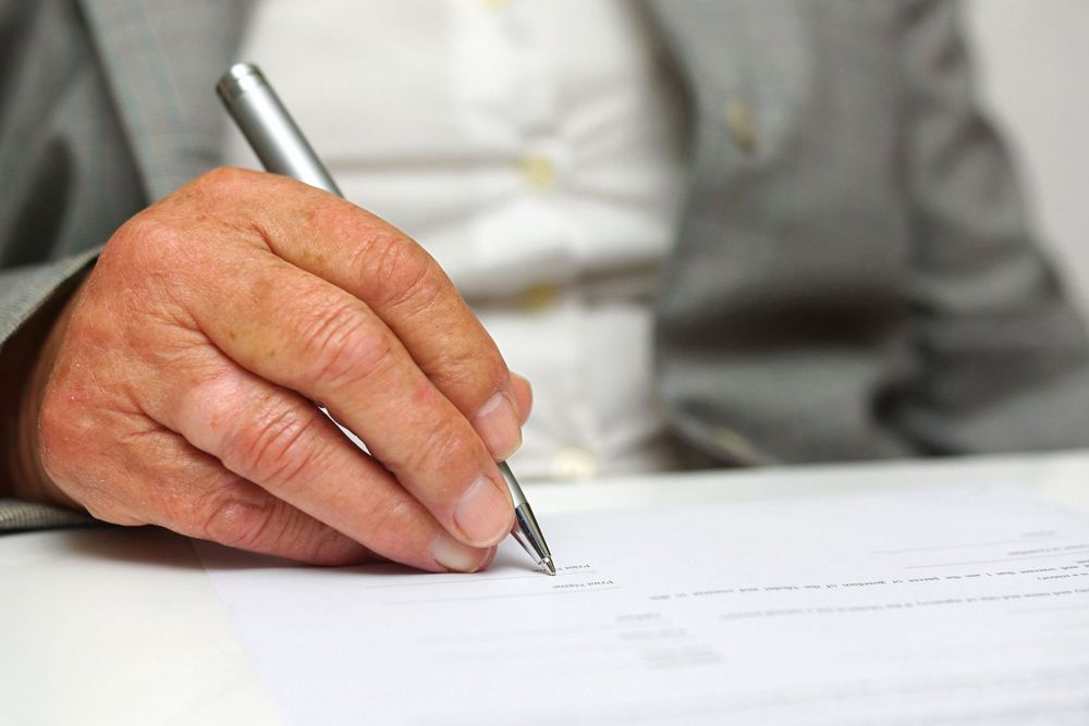 A man is writing on a piece of paper with a pen