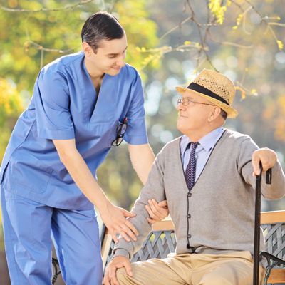 A nurse is talking to an elderly man in a wheelchair.
