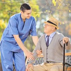 A nurse is talking to an elderly man in a wheelchair.
