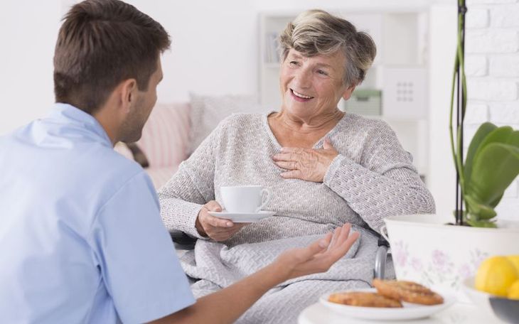 A woman is holding the hand of an older man.