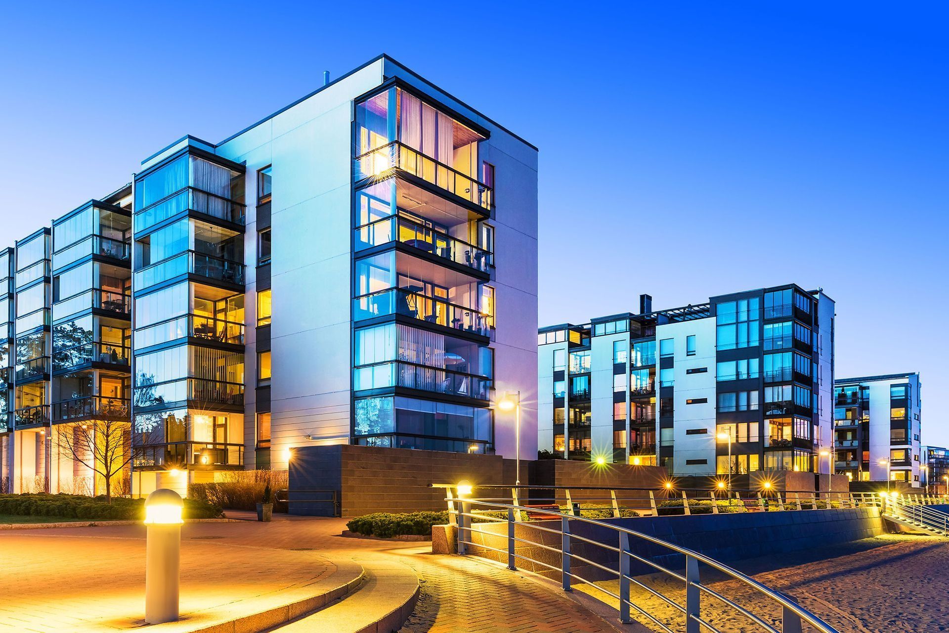Modern apartment buildings with illuminated windows at dusk.