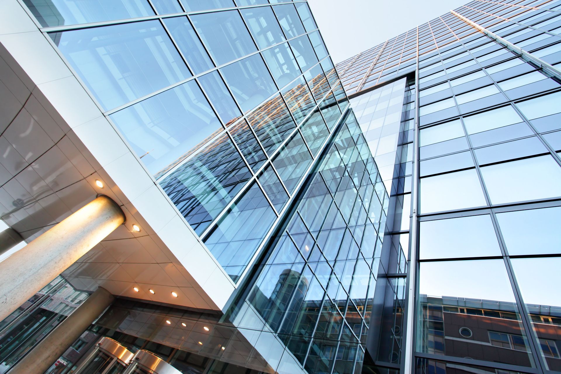Glass and steel skyscraper facade, low angle view with geometric design and sky reflection.