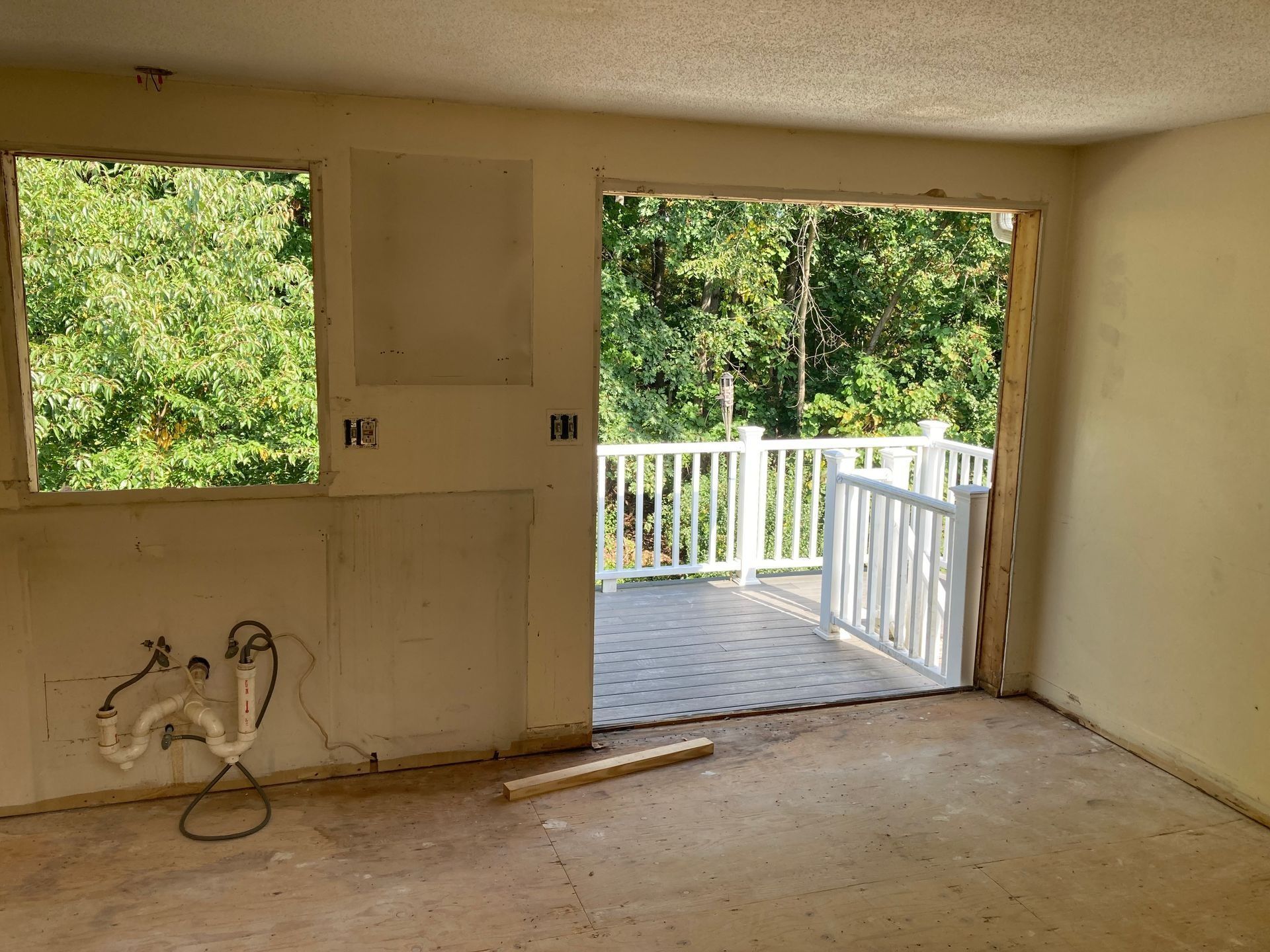 Interior room with unfinished walls and an opening to a deck overlooking trees.