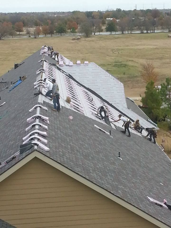 Roofers installing shingles on a residential roof in an outdoor setting.