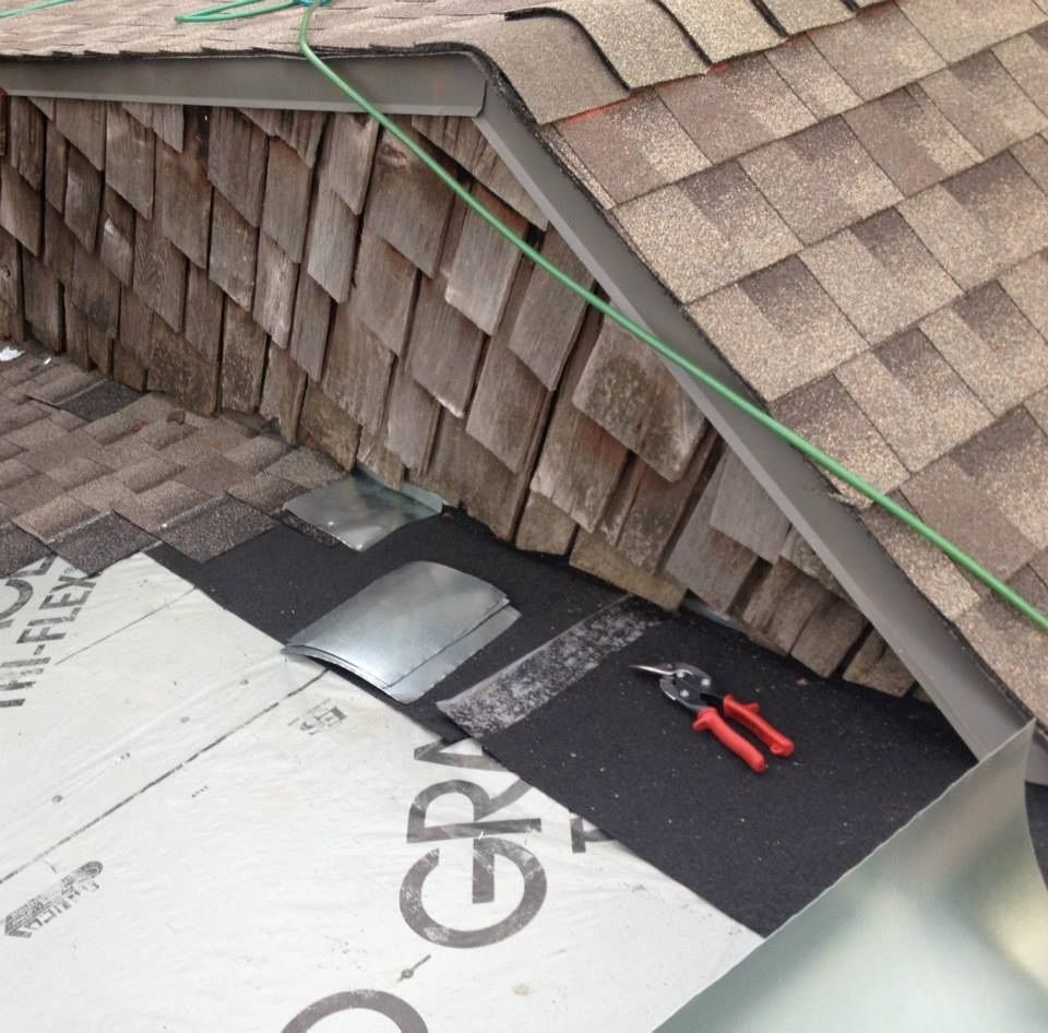Roof repair in progress; metal flashing, scissors, and new shingles.