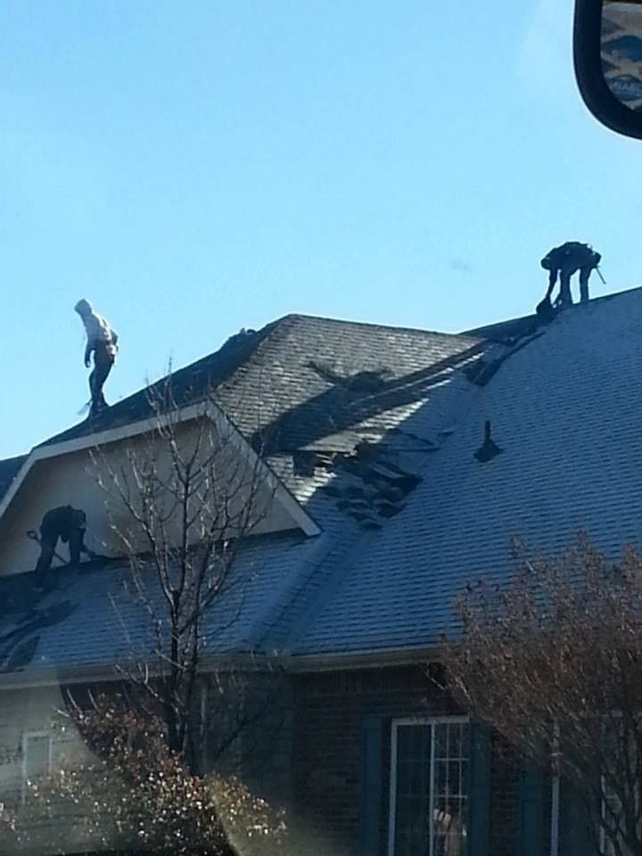 Roofers working on a residential roof under a clear, blue sky.