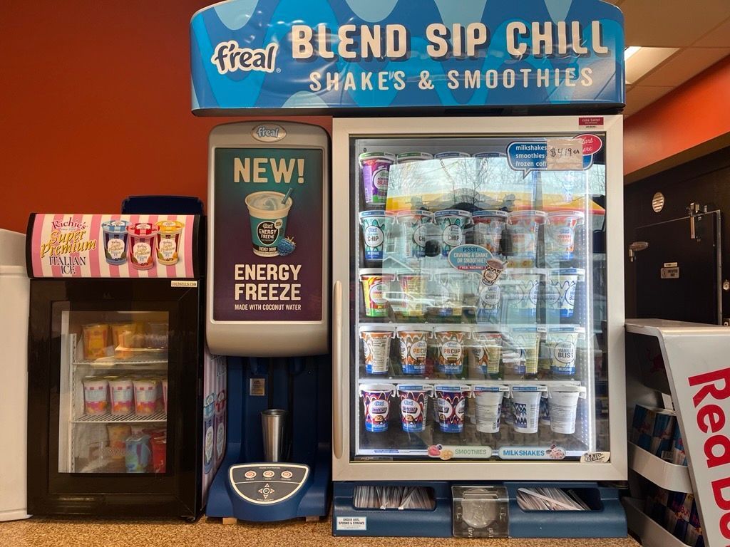A vending machine selling drinks and smoothies in a restaurant.