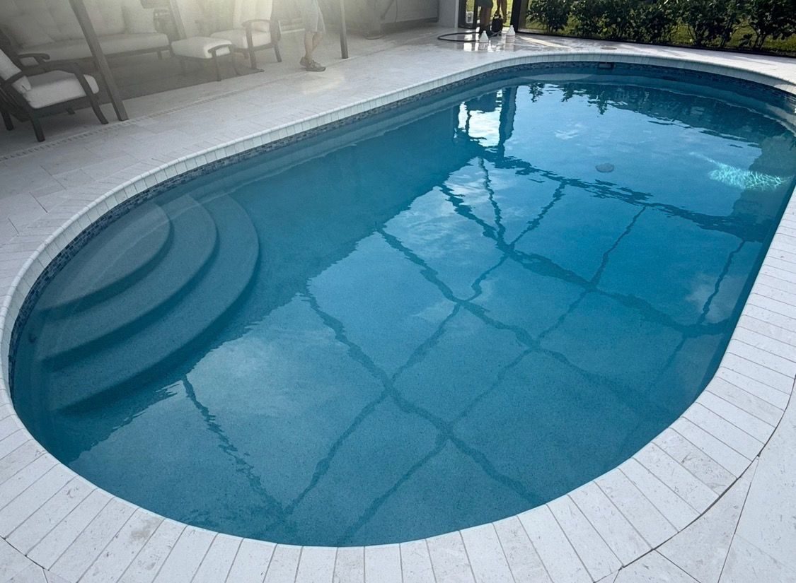 Backyard swimming pool with clear blue water, curved steps, and light stone decking