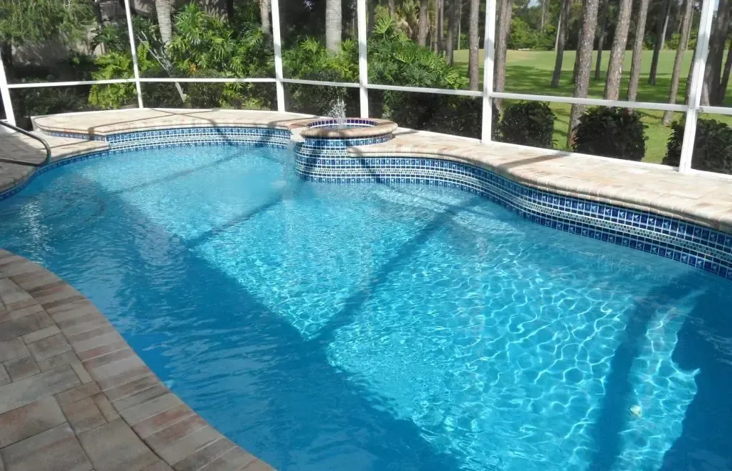 Swimming pool with blue water and tiled edges, enclosed by a white-framed screen.