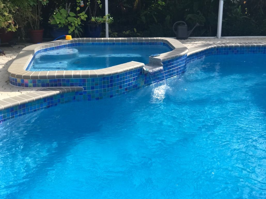 Blue swimming pool with connected hot tub. Blue tile accents the edges. Bright sunny day.