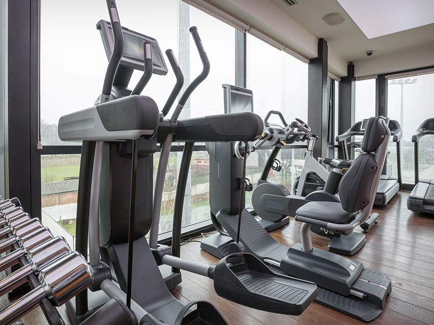 A gym with a lot of exercise equipment and a lot of windows.