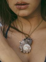 A woman is wearing a necklace with a shell pendant.