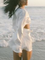 A woman in a white dress is standing in the ocean.