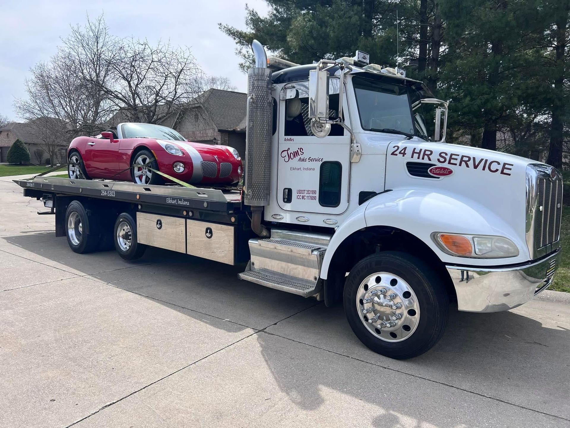 Red sports car on a flatbed tow truck. White truck with 