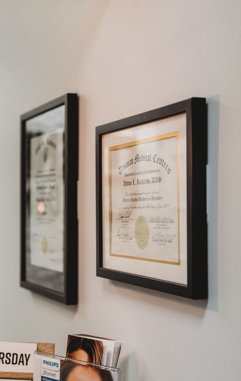 Two framed diplomas are hanging on a wall next to a mirror.