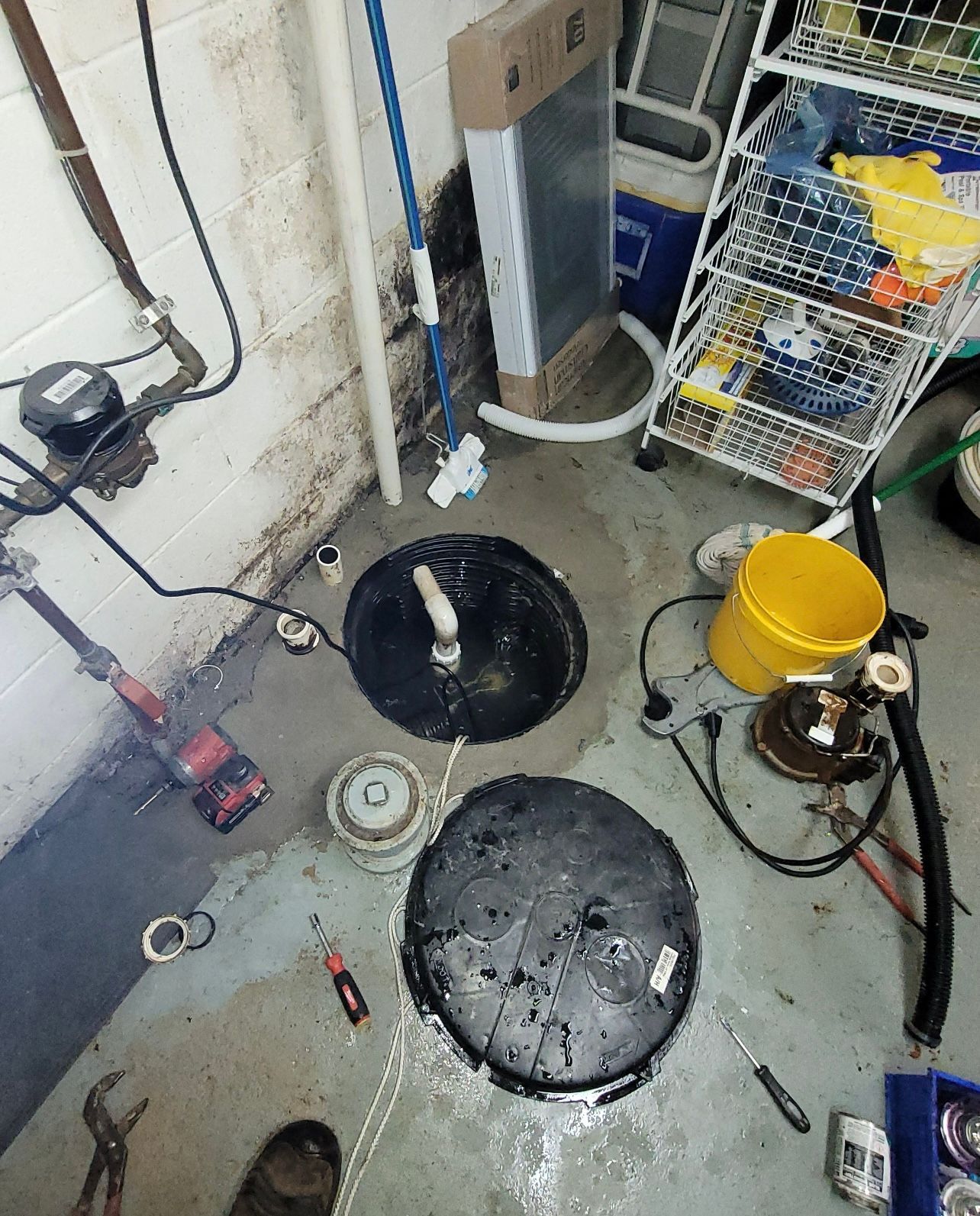 a dirty basement with a yellow bucket and a bucket of water on the floor