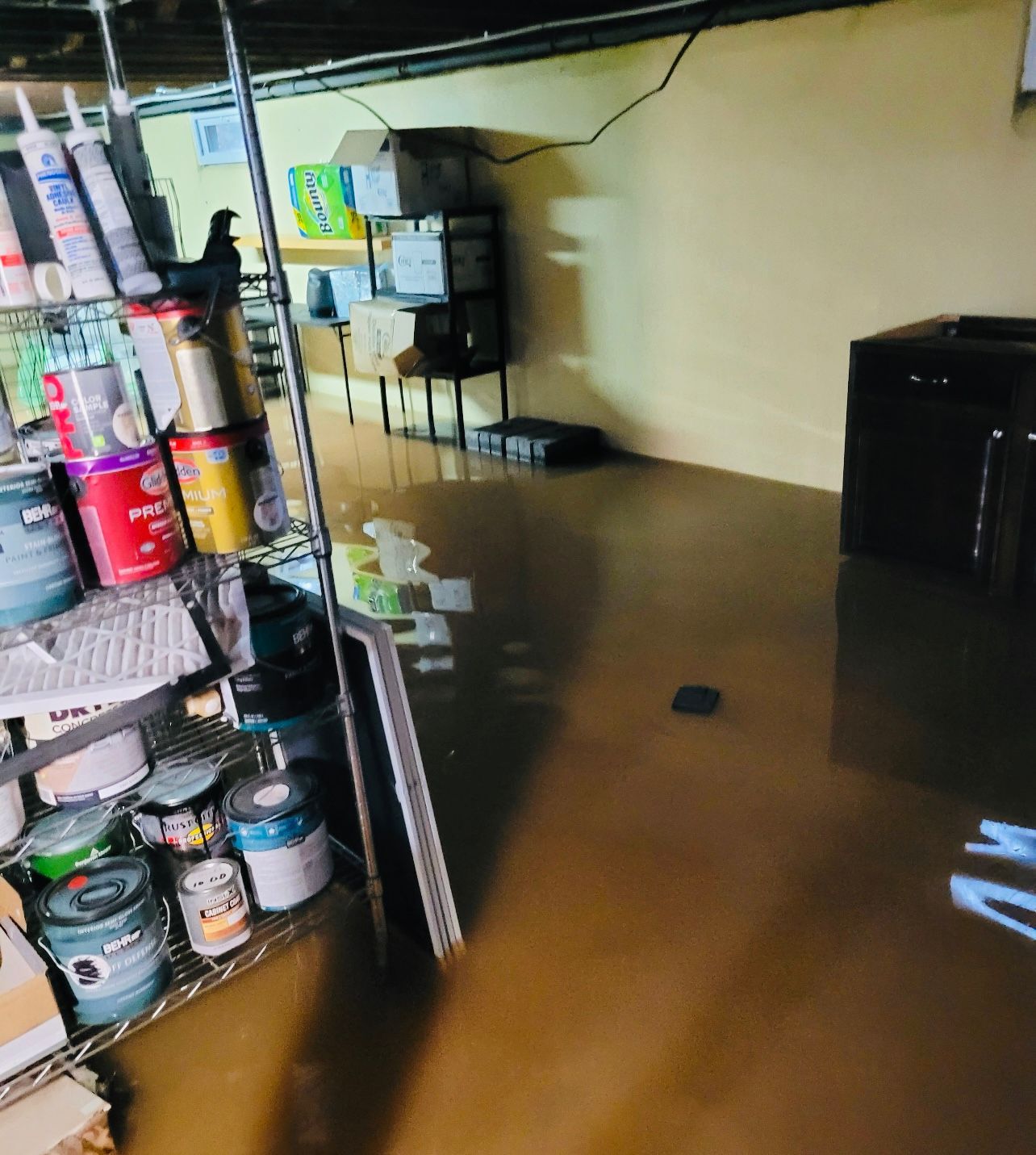 a flooded basement with a shelf full of paint cans