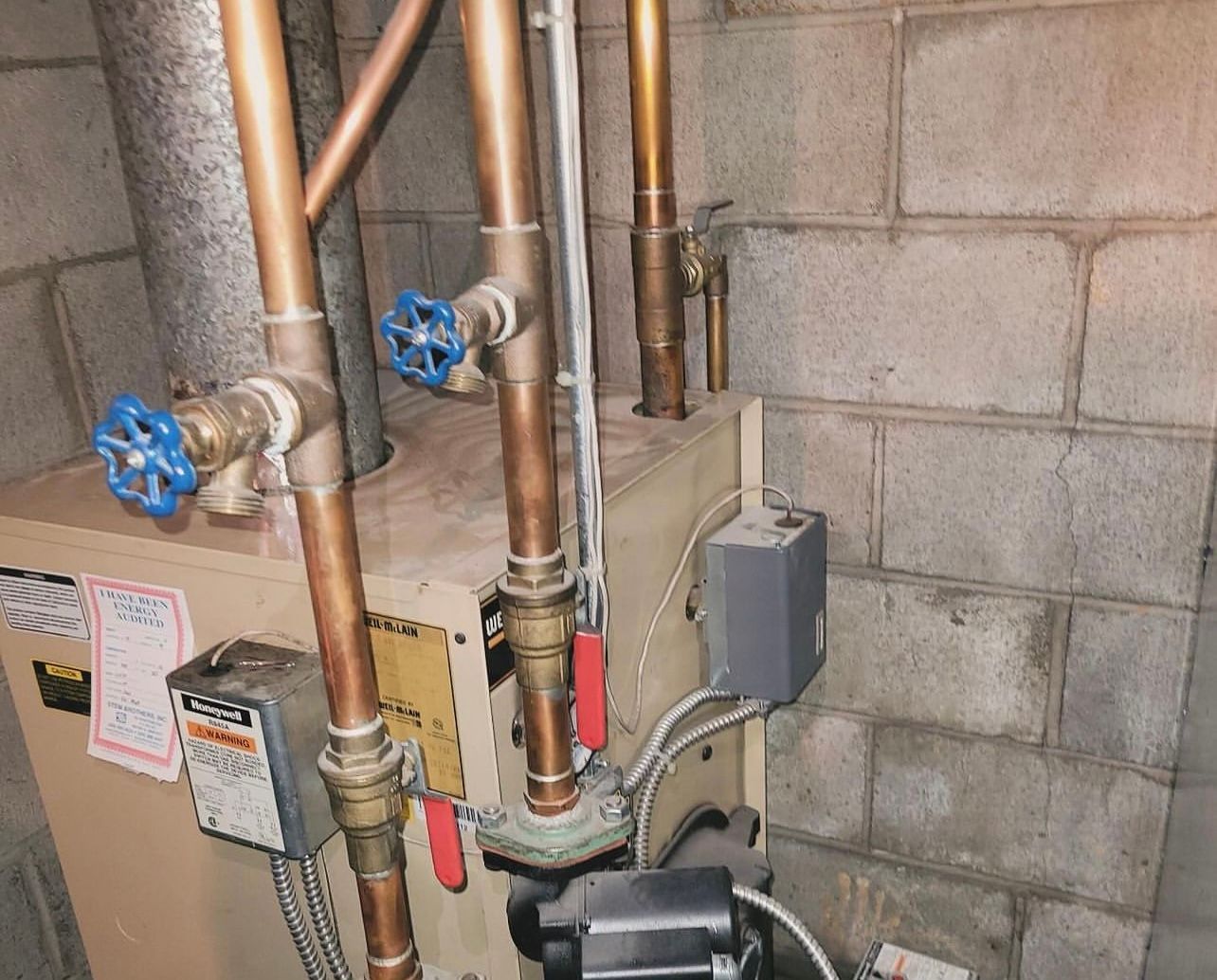 a boiler with copper pipes and valves in a basement