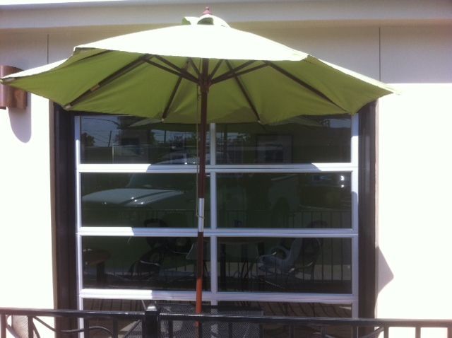 Green patio umbrella in front of a windowed building facade