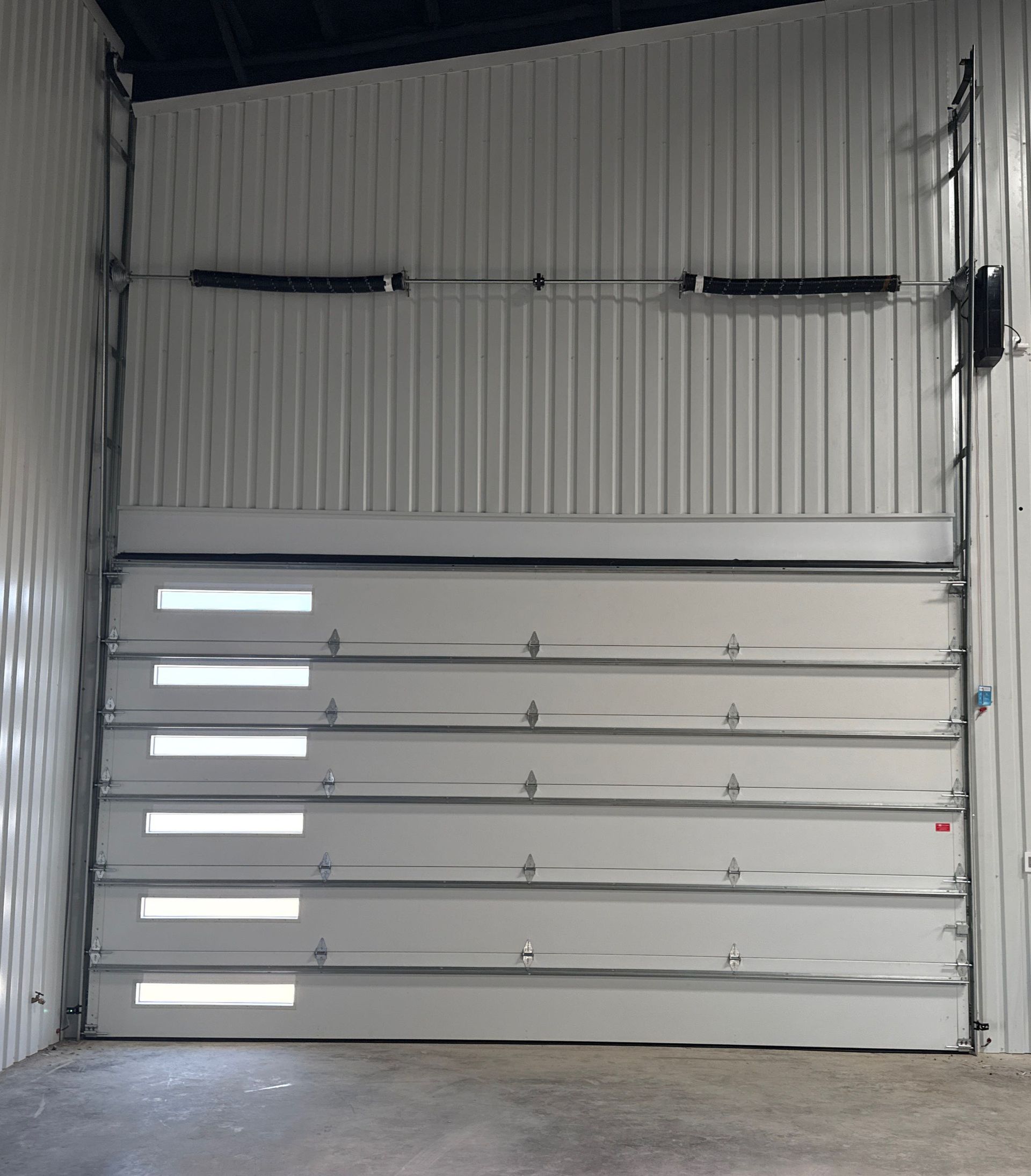 Interior of a closed gray industrial garage door in a corrugated metal warehouse
