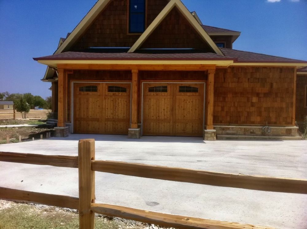 Wooden building with double garage doors behind a wooden fence on a sunny day