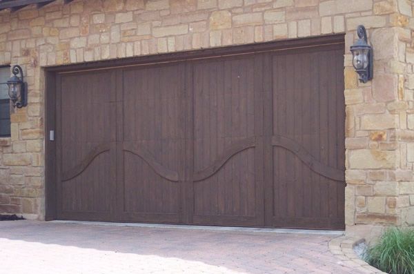 Wooden double garage door with curved design on a stone house facade