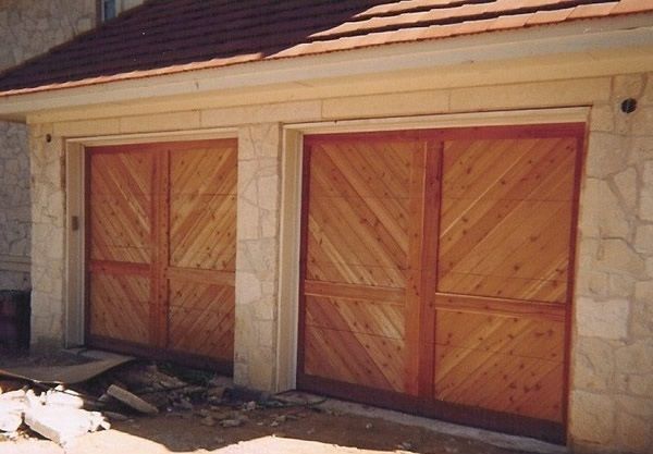 Two wooden garage doors on a stone house with a red-tiled roof