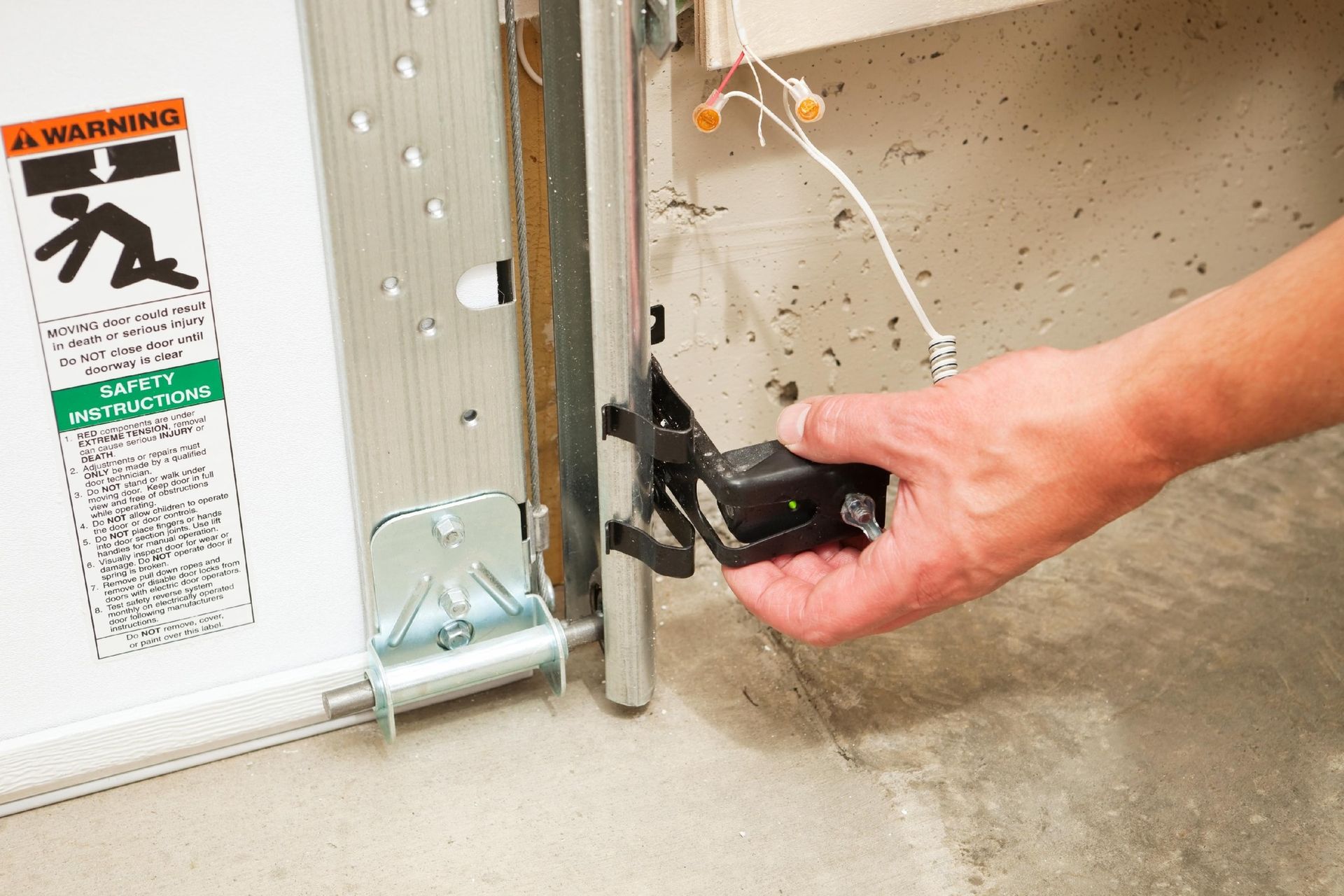 Hand using a black ratchet strap to secure metal furniture frame to a wall in a room