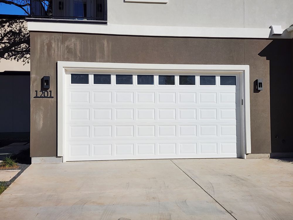 White double garage door on a beige house with driveway in front