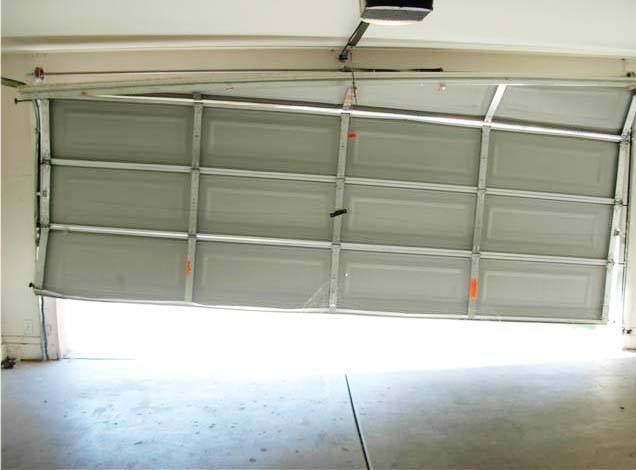 Partially open white garage door with bright daylight spilling into a concrete garage