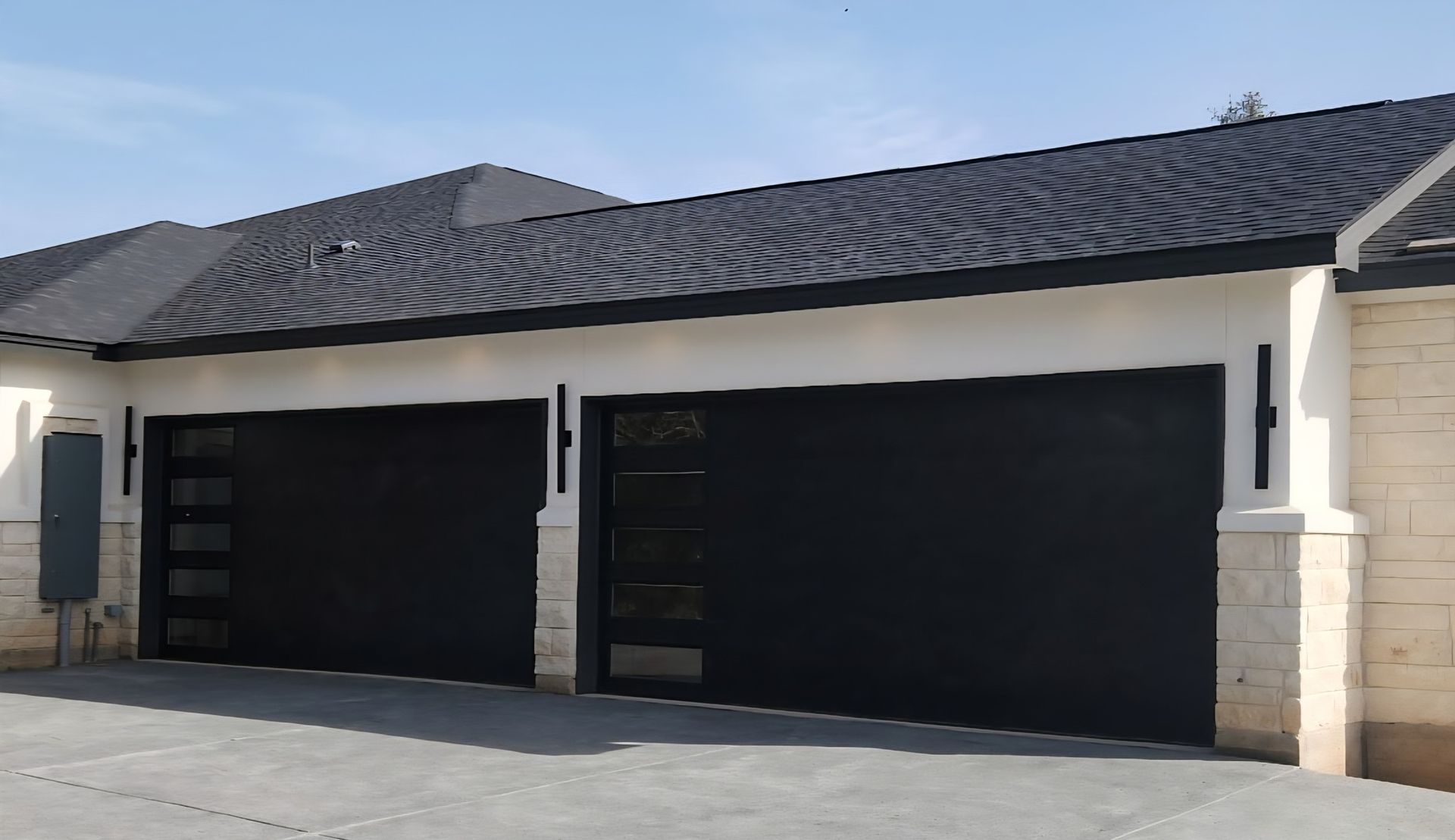 Two black garage doors on a beige suburban house with a dark tiled roof and driveway