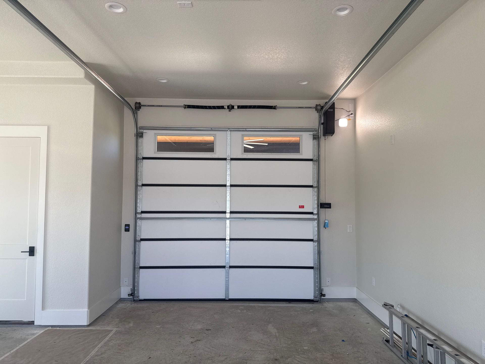 Empty garage interior with a white roll-up door and light gray walls