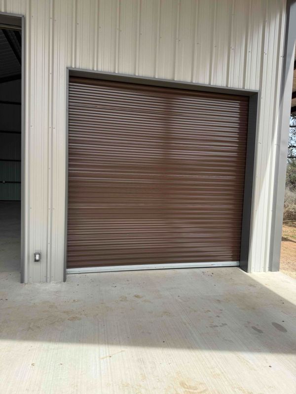 Closed brown roll-up garage door in a metal building exterior.